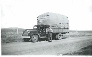 A sepia-toned photo of a 40's era Leduc Truck Service truck with it's proud operator standing beside.