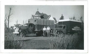 A decades-old picture of two men in shirtsleeves stand proudly in front their 40's era truck fleet.