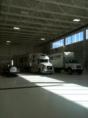 A cube truck and tractor-trailer unit appear dwarfed by the cavernous Leduc Truck Service warehouse.